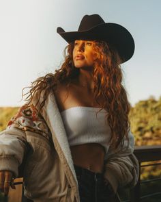 Woman in a cowboy hat and tube top with long curly hair at golden hour