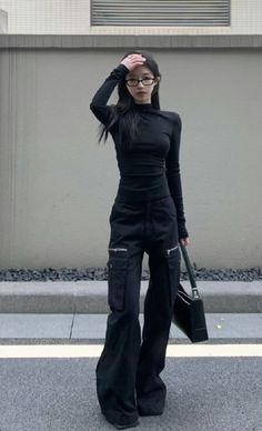 Woman in a black long-sleeve top and cargo pants with glasses outdoors