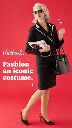 Woman in a black suit and sunglasses holding a magazine and handbag