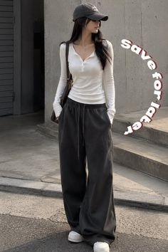 Woman in a white long sleeve shirt and wide leg pants with a baseball cap outdoors