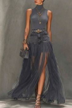 Woman in a gray turtleneck top and a denim and tulle skirt with a high slit