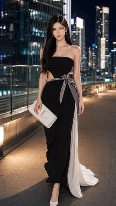 Woman in a black and white strapless dress with cutouts in a city at night