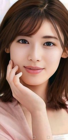 Woman with brown hair and a pink top, with her hand gently touching her face