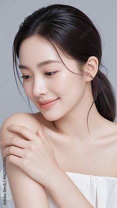 Woman with black hair and exposed shoulders against a plain background