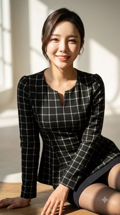 Woman in a black and white plaid dress smiling indoors with soft lighting