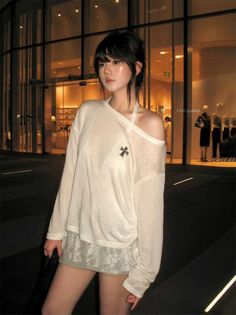 Woman in an off-shoulder top and lace-trim skirt on a city street at night