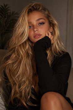 Woman with long blonde hair and blue eyes in a black top with soft lighting