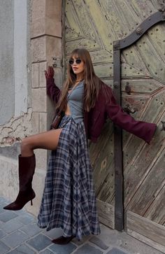 Woman in a plaid skirt and crop top posing against an old wooden door