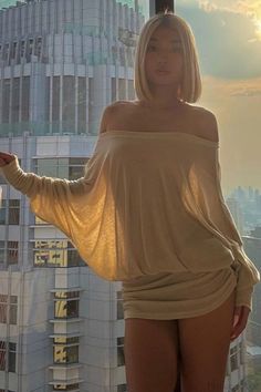 Woman with blonde bob hair in an off-shoulder top against a city background