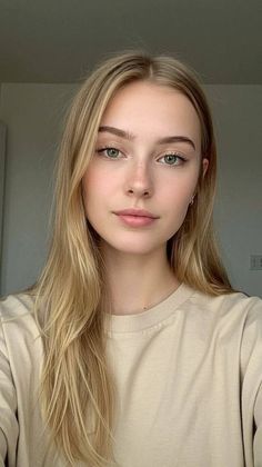 Young woman with long blonde hair and green eyes wearing a beige t-shirt