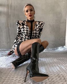 Woman in a houndstooth dress and knee-high boots posing indoors
