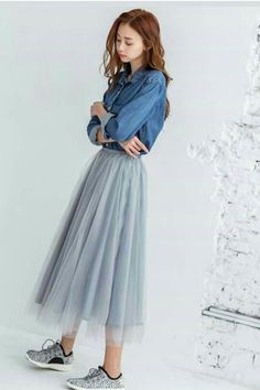 Woman in a denim shirt and a grey tulle skirt posing indoors