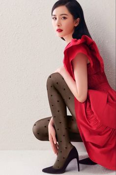 Woman in a red dress and heart-patterned tights posing indoors