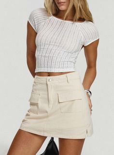 Woman in a white sheer crop top and beige mini skirt