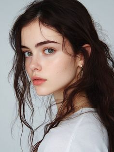 Woman with long wavy dark hair, green eyes, and freckles wearing a white shirt