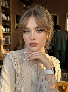 Woman with green eyes and a nose ring wearing a lace blouse indoors