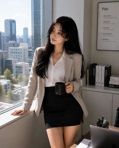 Woman in business attire holding a mug, looking out an office window at a cityscape