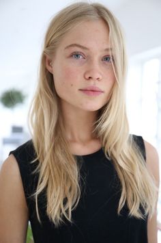 Young woman with blonde hair and freckles wearing a black top