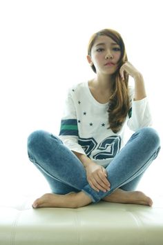 Woman with long hair sitting cross-legged on a light-colored surface