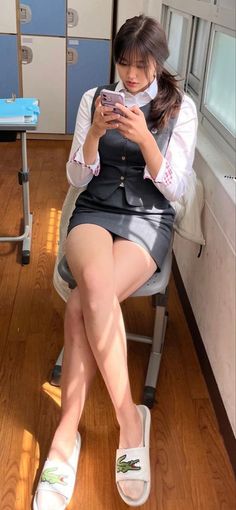 Woman in a school uniform sitting indoors with crossed legs