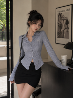Woman with a bun hairstyle wearing a striped shirt and mini skirt indoors