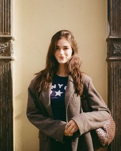 Woman with long brown hair wearing an oversized blazer and t-shirt outdoors
