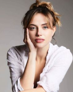 Woman with blonde hair in a messy bun wearing a white shirt, studio portrait