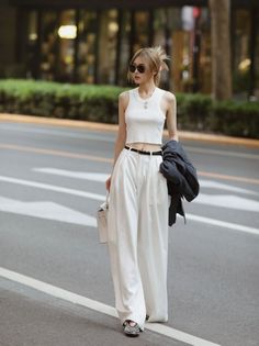 Woman in a white crop top and wide leg pants walking on a street