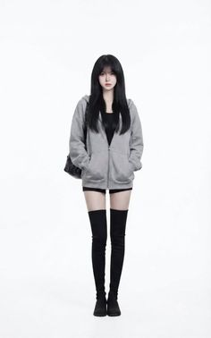 Woman with long black hair wearing a grey hoodie, black shorts, and thigh-high boots