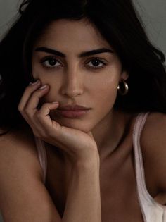 Woman with long dark hair and gold hoop earrings in a pink camisole