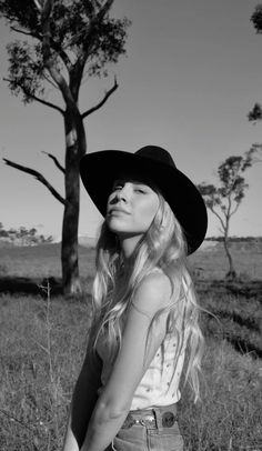 Woman in a cowboy hat with long blonde hair in a grassy field
