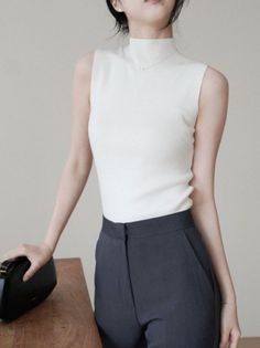 Woman in a white sleeveless high-neck top and dark pants