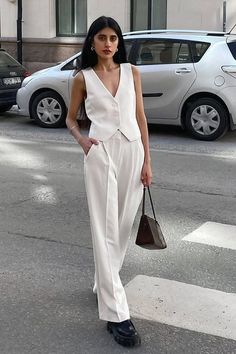 Woman in a white suit and chunky shoes on a street with cars in the background