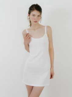 Woman in a white slip dress with lace trim against a white background