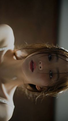 Woman with wet hair and a white top looking directly at the viewer