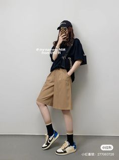 Person in a black t-shirt, bermuda shorts, and sneakers taking a mirror selfie