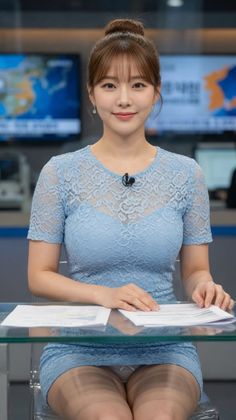 Woman in a blue lace dress with an updo hairstyle sitting at a desk