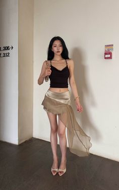Woman with long black hair wearing a crop top and mini skirt indoors