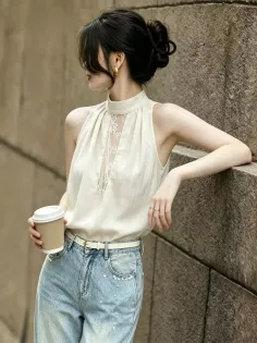 Woman with an updo hairstyle wearing a sleeveless top and jeans, holding a coffee cup