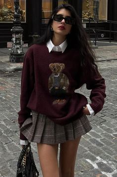 Woman in a teddy bear sweater and plaid skirt on a cobblestone street