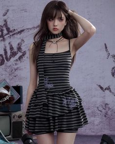Woman in a striped dress with dark makeup and a choker posing indoors