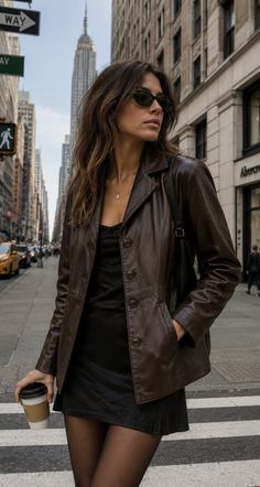 Woman in a brown leather jacket and black dress on a city street