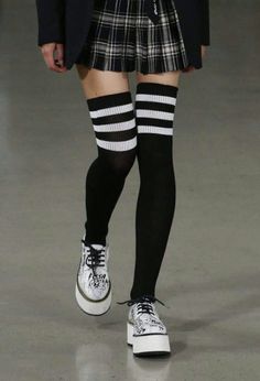 Person wearing a plaid skirt, thigh-high socks, and platform shoes