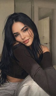 Woman with long black hair wearing an off-shoulder crop top indoors