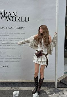 Woman with long wavy hair in a white tiered skirt and cowboy boots outdoors