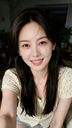 Woman with long black hair wearing a floral top and pearl earrings