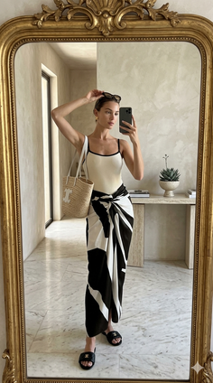 Woman in a swimsuit and sarong taking a mirror selfie indoors