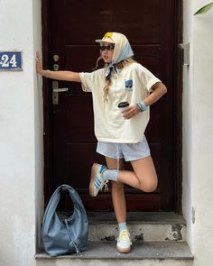 Woman in a scarf and striped shorts posing outdoors with a coffee cup