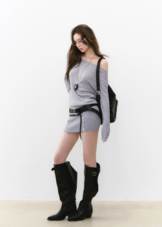 Woman in a gray off-shoulder top and mini skirt with black boots and glasses
