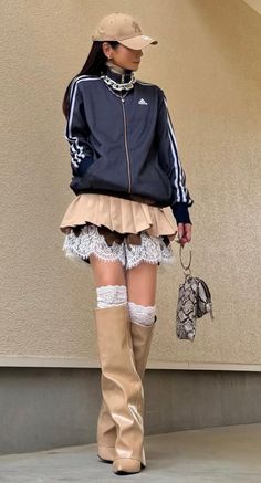 Person in a track jacket, pleated skirt with lace trim, and thigh-high boots